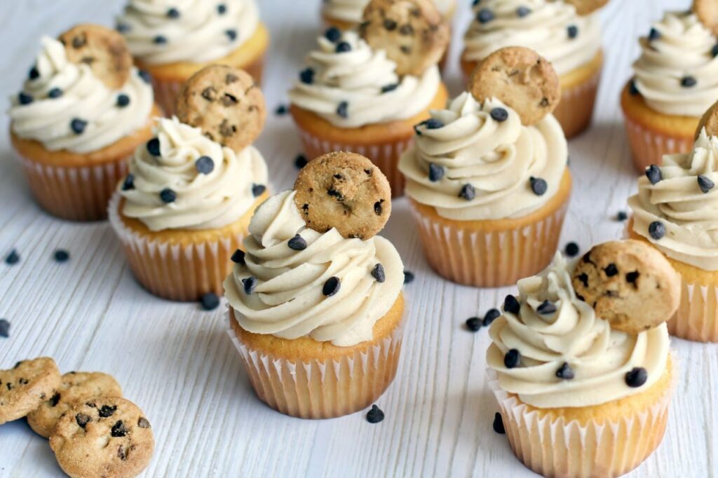 Cookie Dough Cupcakes with Cookie Dough Frosting and mini cookies on top and chocolate chips sprinkled around