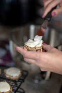 Person putting frosting on a cookie