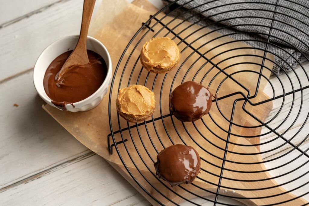 Steps 6-9 visual: put peanut butter on top of circle then freezer. After peanut butter is firm, Pour 1 tbsp. of melted chocolate on top.