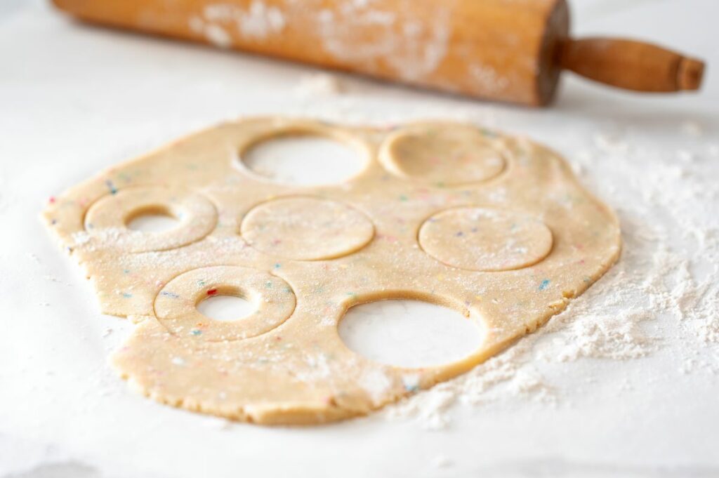 Step 2 - rolled out confetti cookie dough with large circles cut out and a few with the smaller, inner circles cut out.