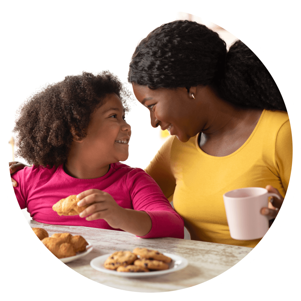 Mother and daughter looking at each other while eating cookies