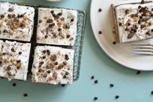 Chocolate Chip Cookie Delight Bars on a cooling rack. One bar is on a plate next to the rack.